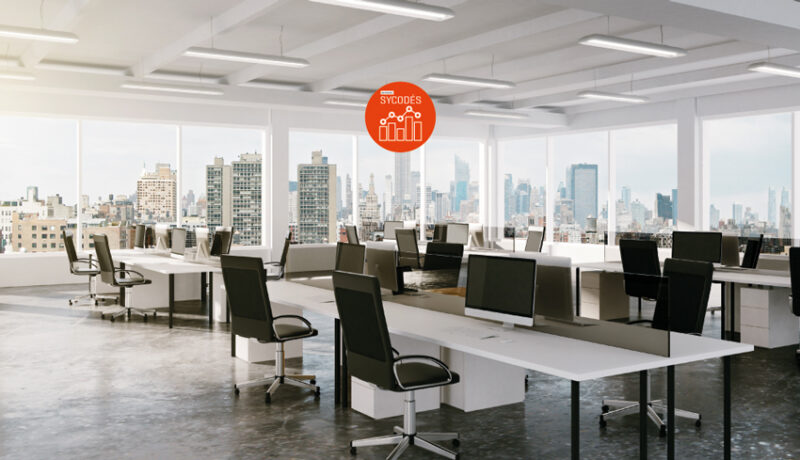 Photo d'un bureau d'espace ouvert moderne avec vue sur la ville. Logo du Dispositif SYCODÉS de l'AQC en haut